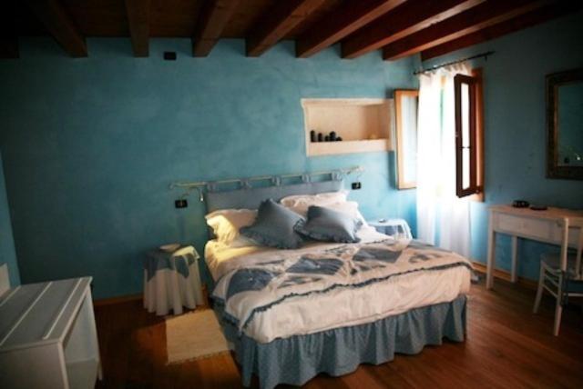 1 dormitorio con 1 cama en una pared azul en La Quiete Bed & Breakfast en Brendola