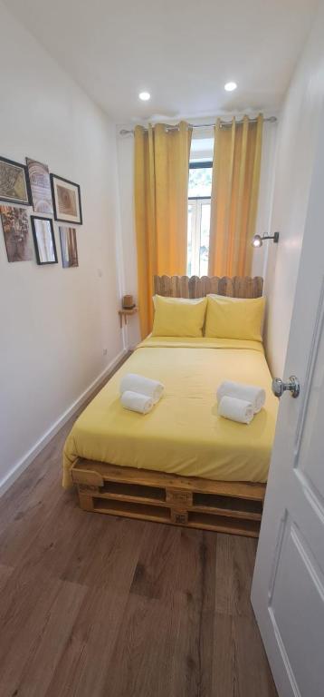 a bedroom with a bed with yellow sheets and a window at S.Soares Yellow Beato in Lisbon