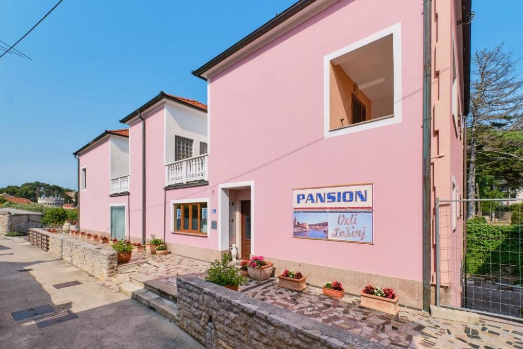 un edificio rosa con un cartello di missione sopra di Rooms with a parking space Veli Losinj, Losinj - 21045 a Veli Lošinj (Lussingrande)