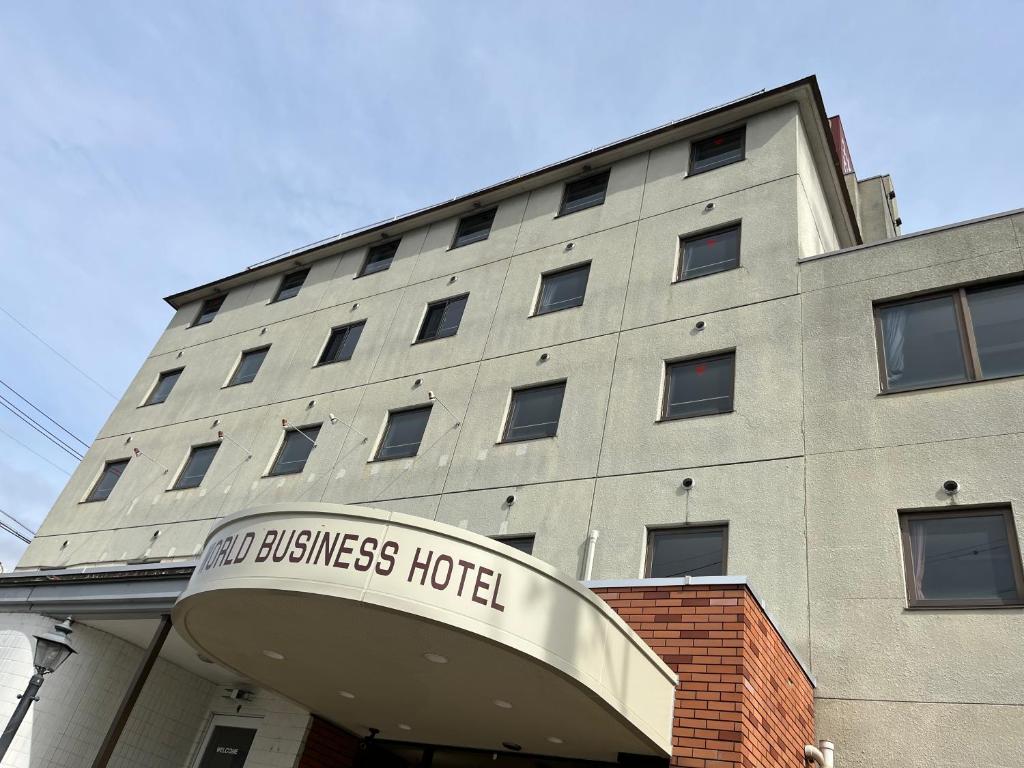 a building with a sign that reads new business hotel at World Business Hotel in Iida