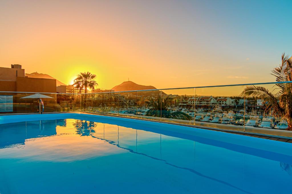 a swimming pool with the sunset in the background at CaboWilson in Cabo San Lucas