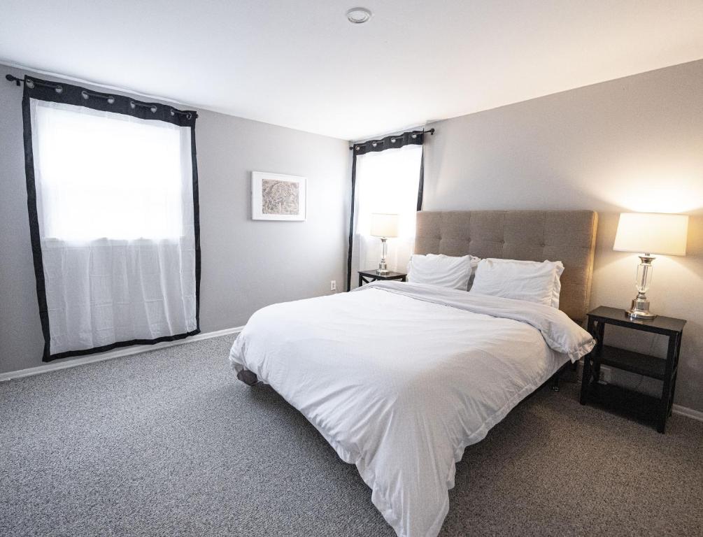 sypialnia z dużym białym łóżkiem i 2 oknami w obiekcie Cheerful home with free parking and WiFi w mieście Rochester