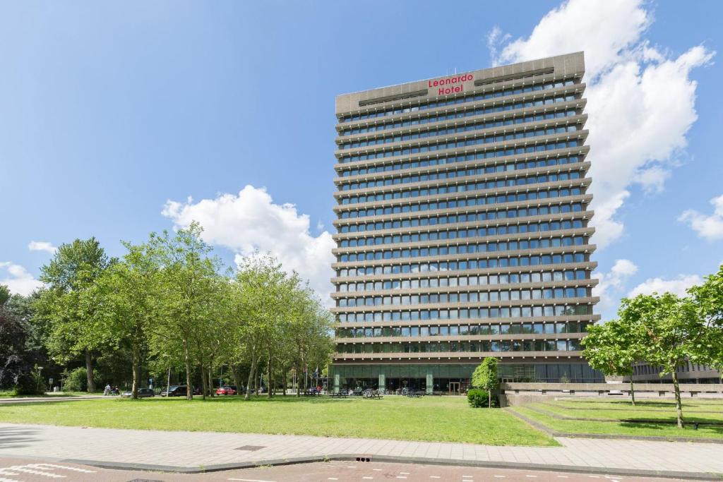 un edificio alto con un parque delante de él en Leonardo Hotel Amsterdam Rembrandtpark en Ámsterdam