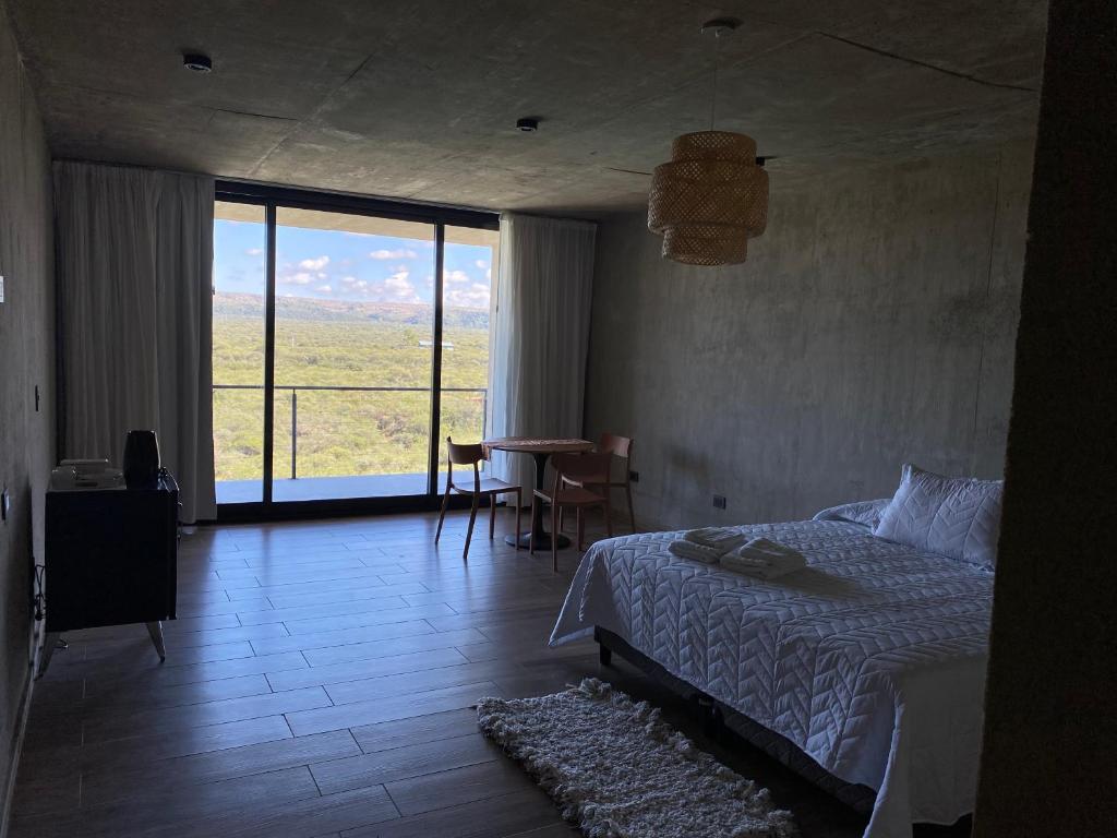 a bedroom with a bed and a table and a large window at Casa Sol in Villa Cura Brochero