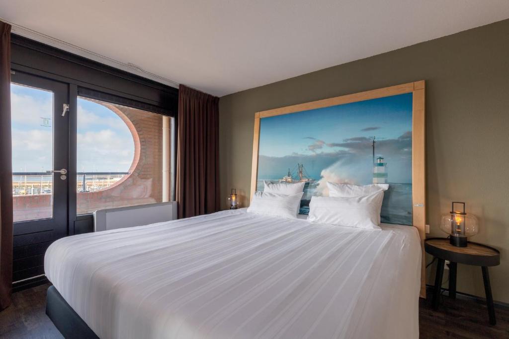 een slaapkamer met een groot wit bed en een groot raam bij Leonardo Hotel IJmuiden Seaport Beach in IJmuiden