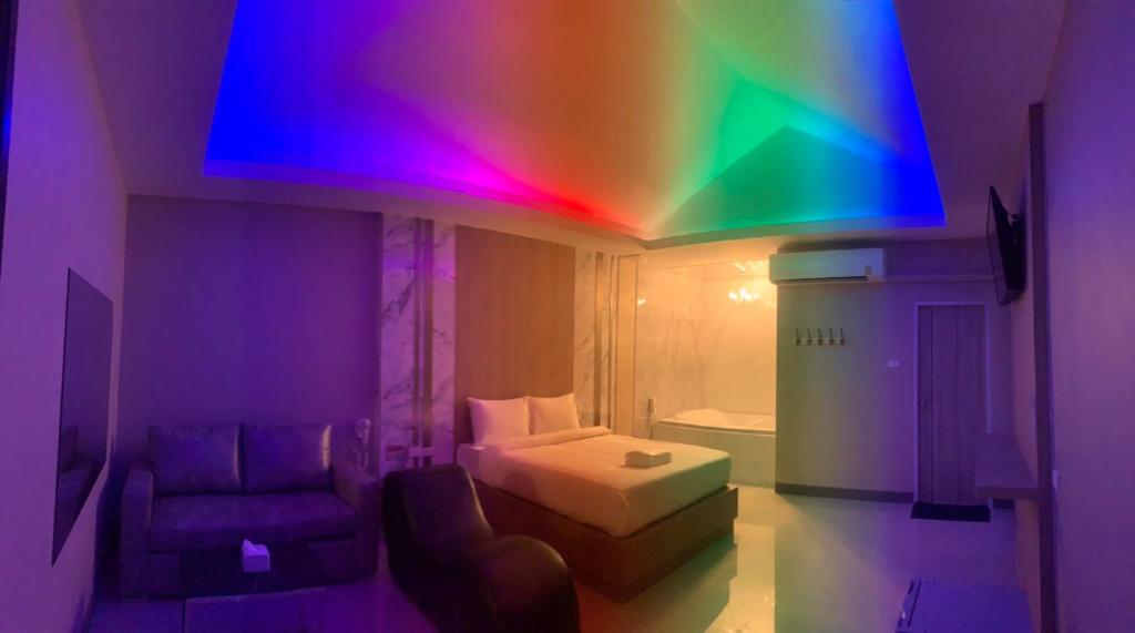 Cette chambre dispose d'un lit et d'un plafond arc-en-ciel. dans l'établissement โรงแรมในฝัน, à Chonburi