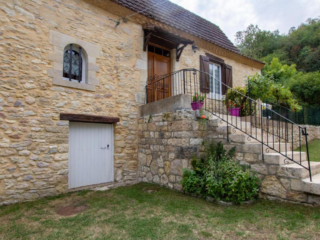 a stone house with a white door and stairs at Maison en pierres avec jardin clos, proche grotte de Tourtoirac, équipements bébé, animaux acceptés. - FR-1-616-280 in Tourtoirac