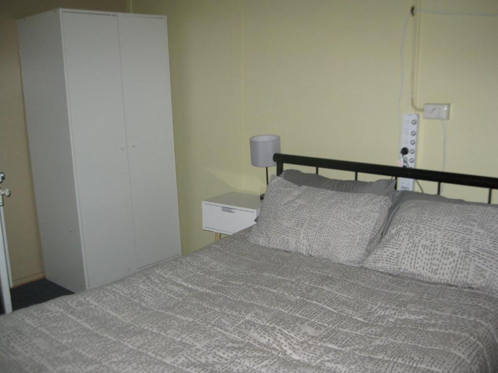 ein Schlafzimmer mit einem Bett und einer Lampe auf einem Tisch in der Unterkunft Australian Hotel Winton Budget Hotel Accommodation in Winton