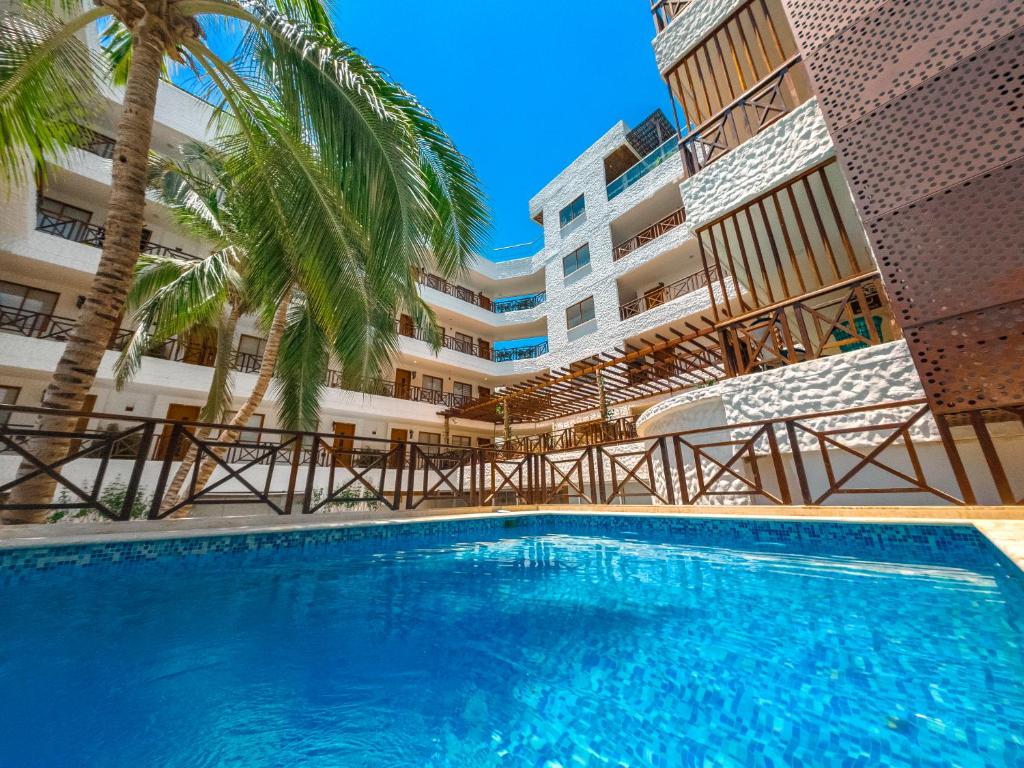 a swimming pool in front of a building with palm trees at HOTEL KARAYA DIVE RESORT in Santa Marta