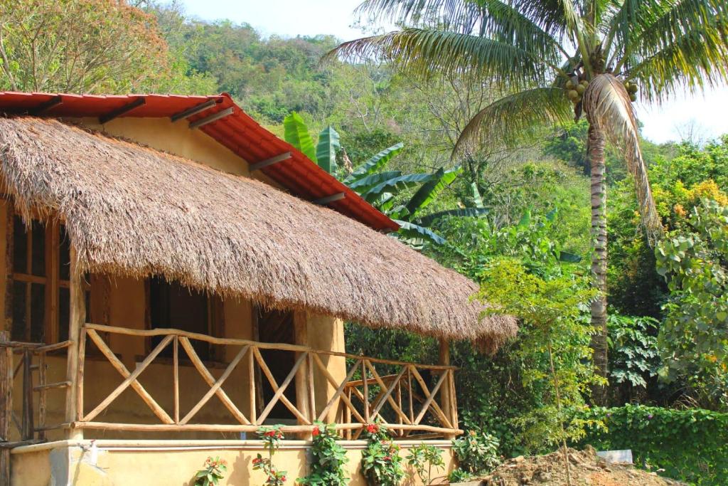 een hut met een rieten dak naast een palmboom bij Ixak Cabañas 