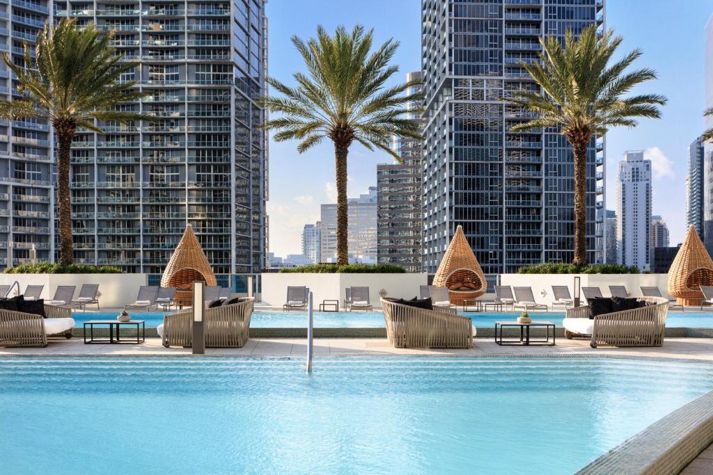 a pool with chairs and palm trees and buildings at Kimpton EPIC Hotel, an IHG Hotel in Miami