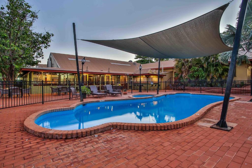 a swimming pool with a umbrella in front of a building at Kimberley Hotel in Halls Creek