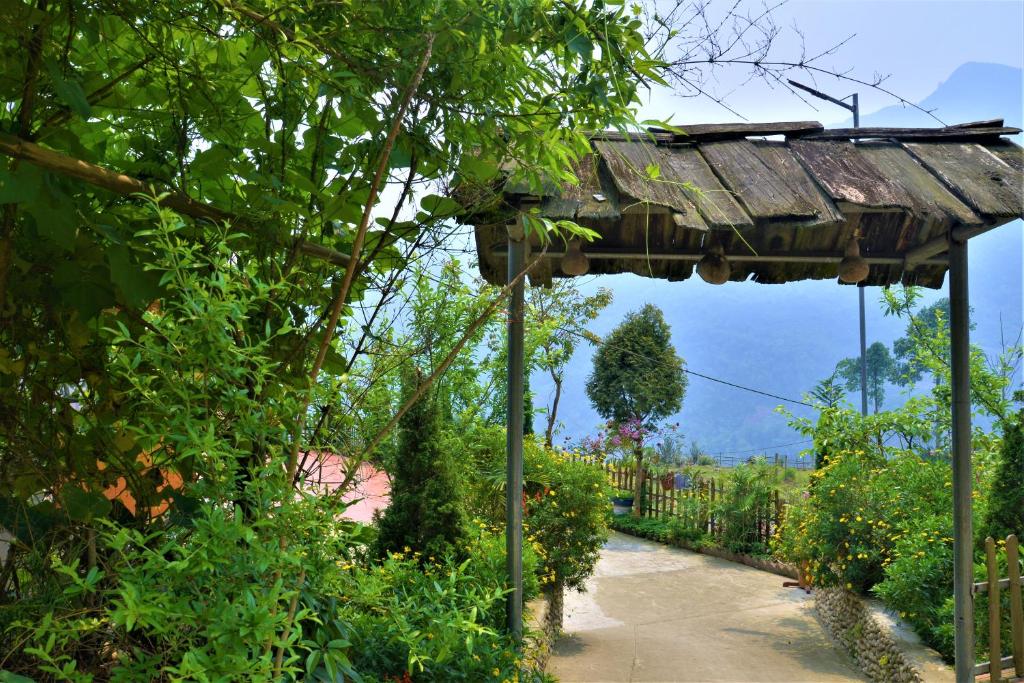 a garden with a wooden pergola and a pathway at Lee's Charm Homestay in Sa Pa