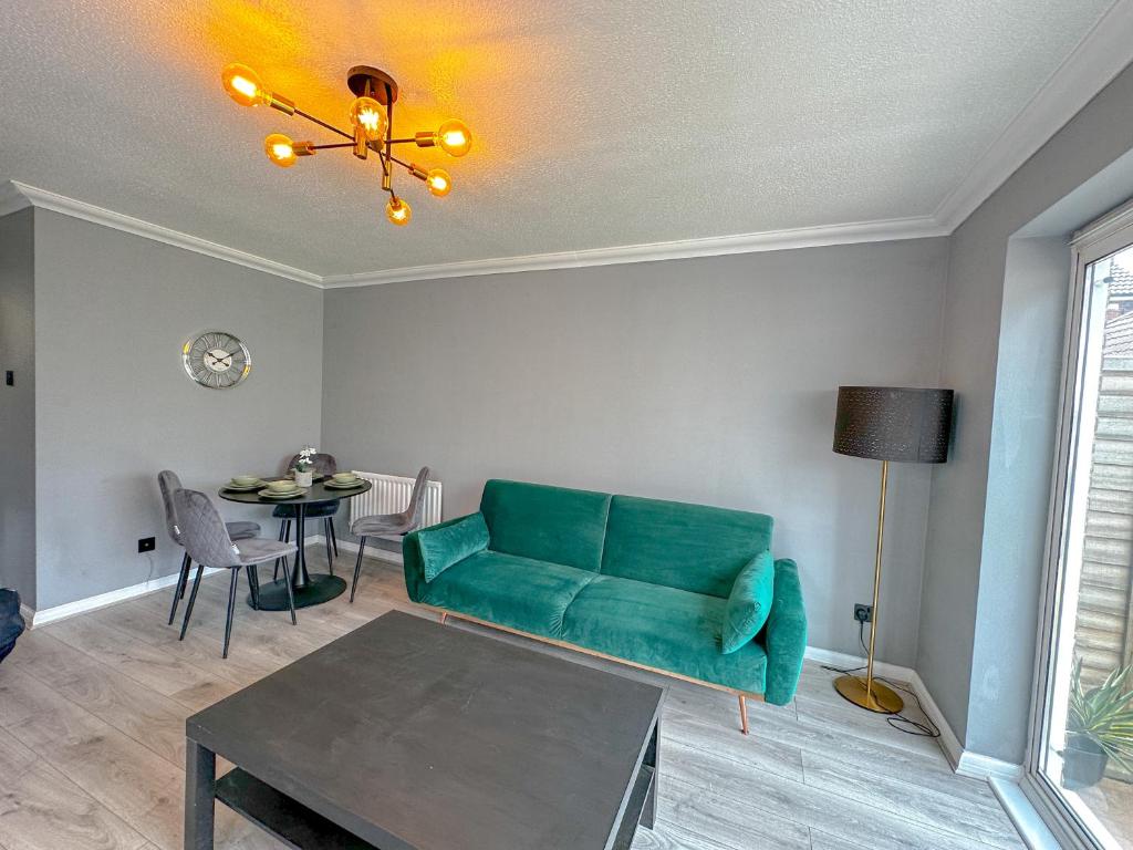 a living room with a green couch and a table at New Stylish 2 Bedroom House in Kent