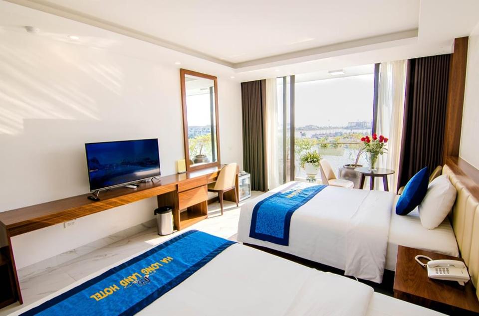 a hotel room with a bed and a desk with a television at Hạ Long Land Hotel in Ha Long