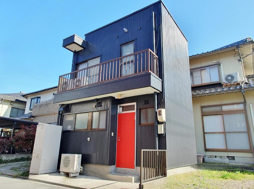 um edifício com uma porta vermelha e uma varanda em Whole house rental 一棟貸切宿 "Your Home Tottori" 市内中心地近くの素敵な一軒家 em Tottori