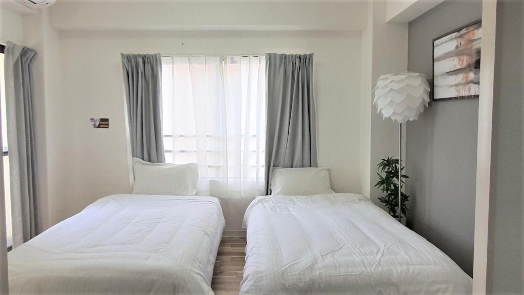 two beds in a small room with a window at Sun Park Heights in Kobe