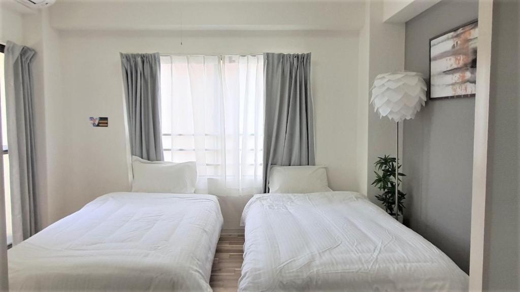 Dos camas en una habitación pequeña con ventana. en Sun Park Heights, en Kobe