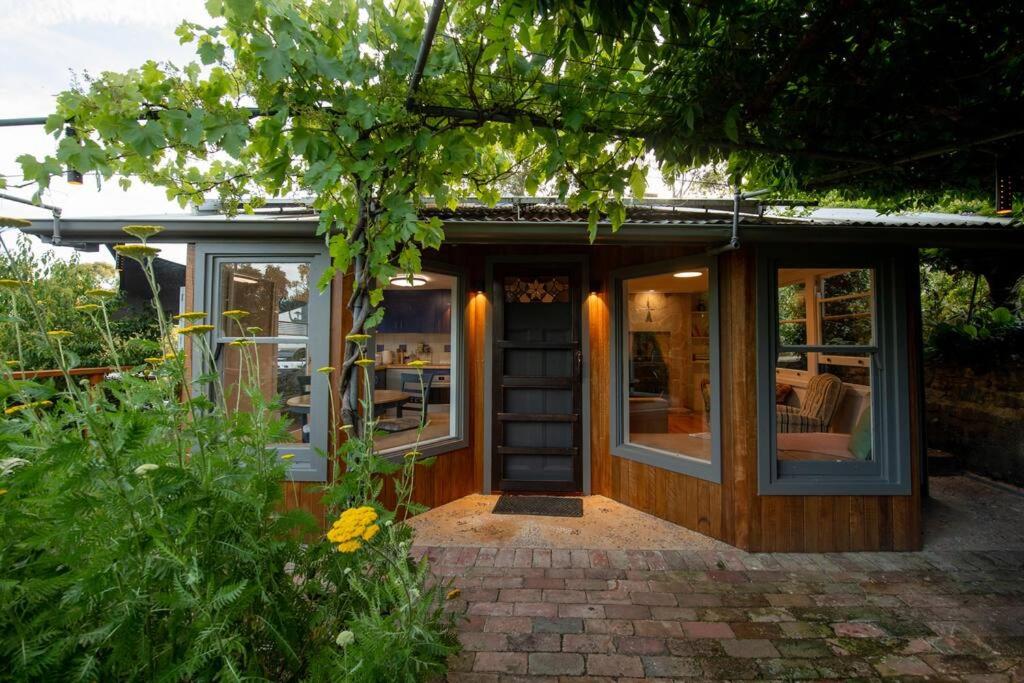 ein kleines Haus mit einer Tür und Fenstern in der Unterkunft Delphi, Adelaide Hills Garden BnB in Mylor