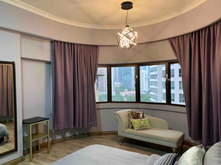 a living room with a couch and a chair and windows at Cosy City Centre Living at WTC in Kuala Lumpur