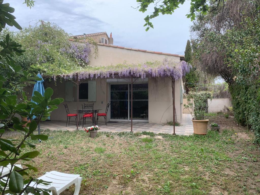 uma casa com um pátio com uma mesa e flores roxas em Les jonquiers, gîte indépendant cosy avec jardin em Aubagne