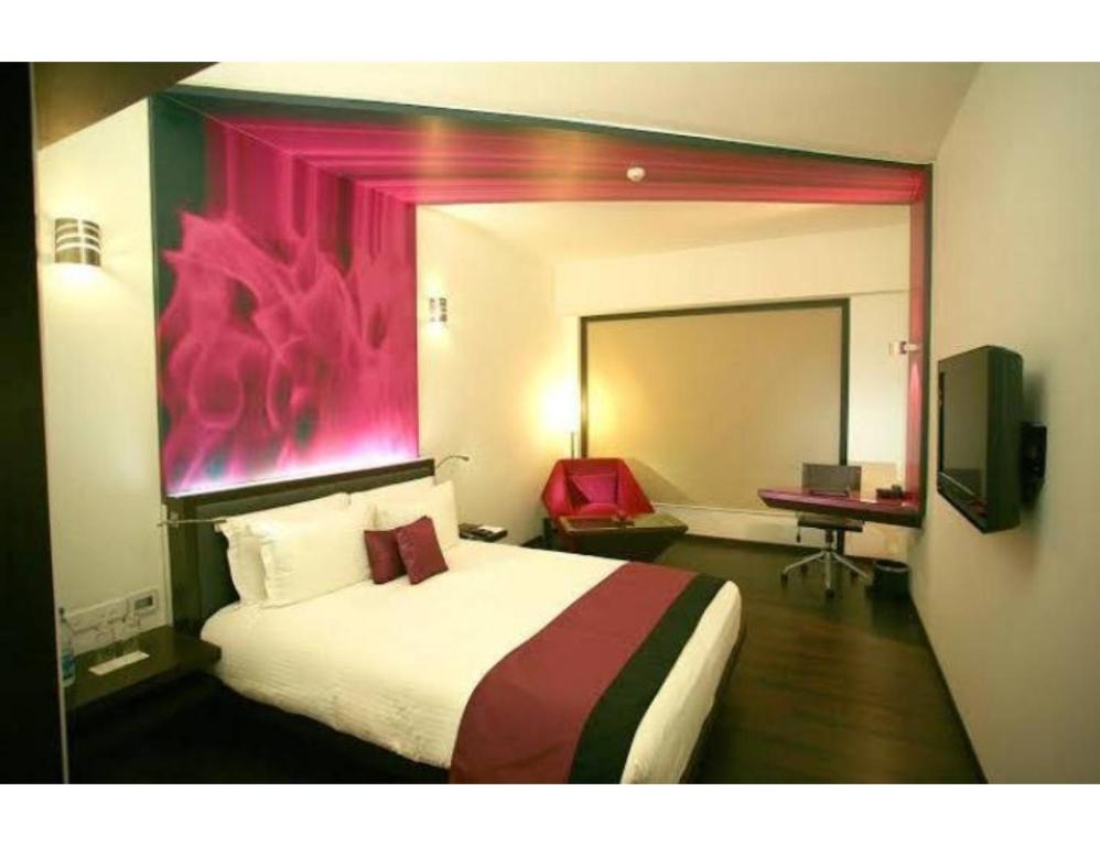 a bedroom with a large bed with a pink painting on the wall at Hotel Vivek, Prayagraj in Muthiganj