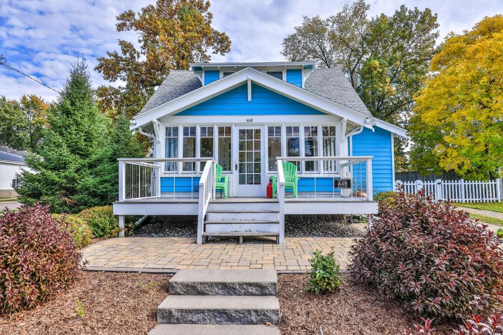 Casa azul con porche delantero con 2 sillas en The Blue Cottage, en Minocqua