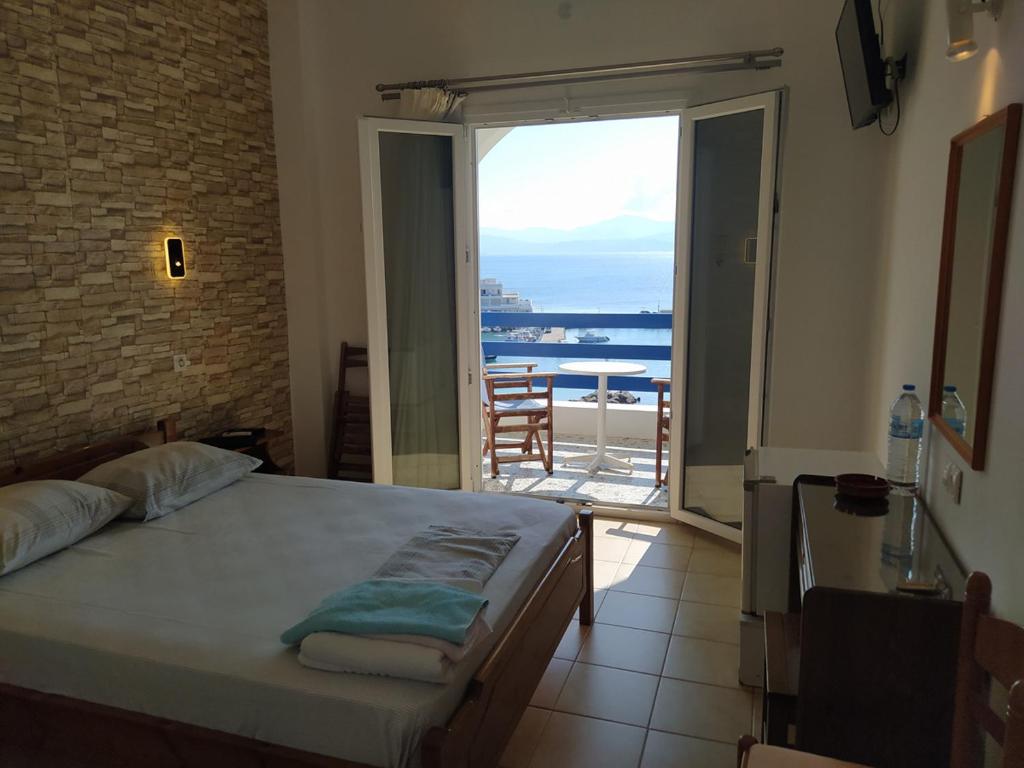 a bedroom with a bed and a view of the ocean at Corali Hotel in Piso Livadi