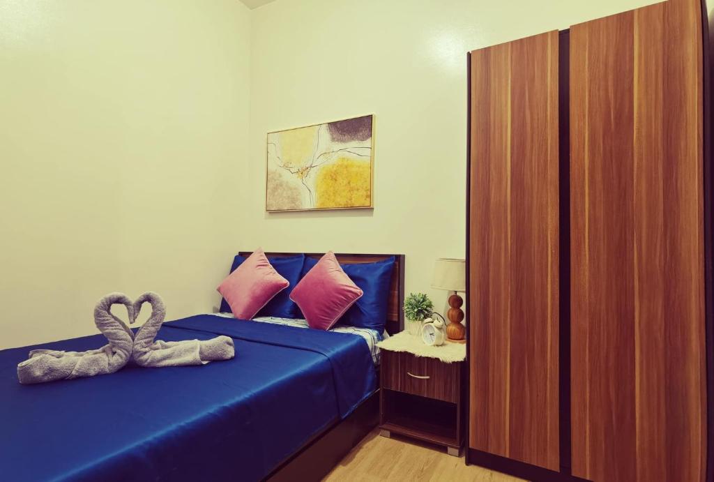 a bedroom with a blue bed with a heart pillow at Condominium at Spring Residences near Airport in Manila