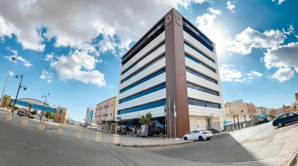 une voiture blanche garée devant un bâtiment dans l'établissement DIFFERENT HOTEL, à Tabuk