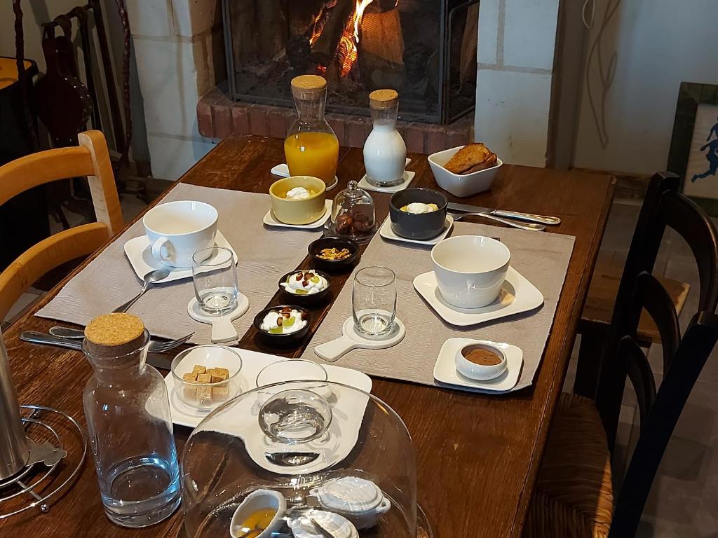 una mesa de madera con alimentos para el desayuno y bebidas. en Maison du Lys en Layon en Les Cerqueux-sous-Passavant