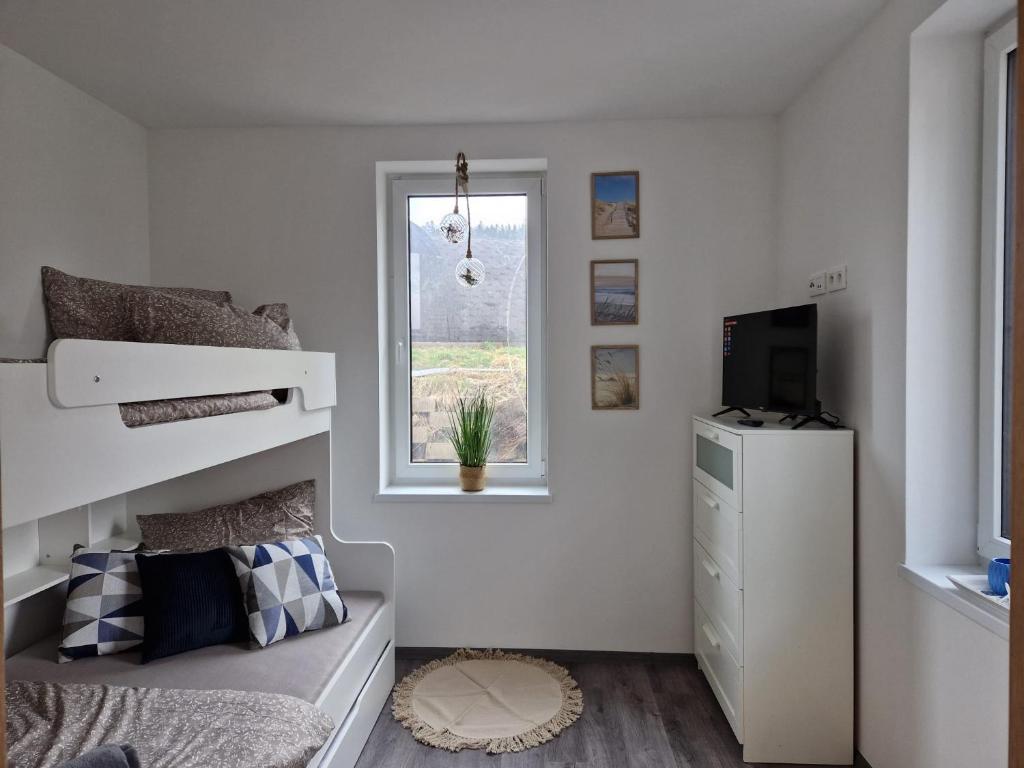 een witte slaapkamer met een stapelbed en een raam bij Apartmán Jestřábí Lipno in Černá v Pošumaví