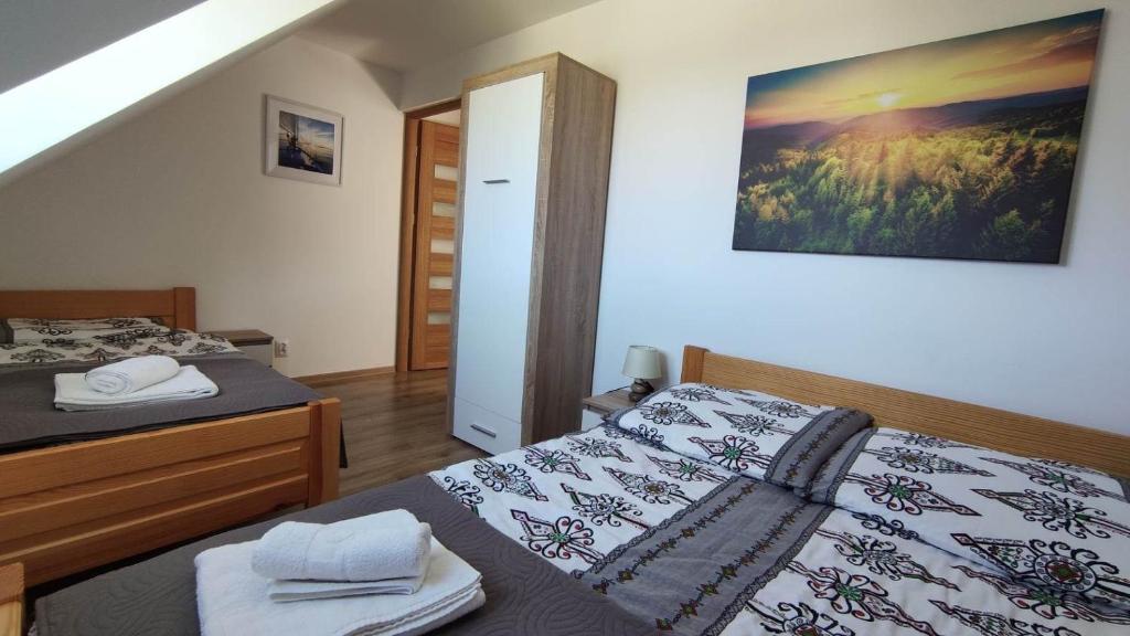 a bedroom with two beds and a picture on the wall at Apartamenty Zatoka Relaksu in Polańczyk