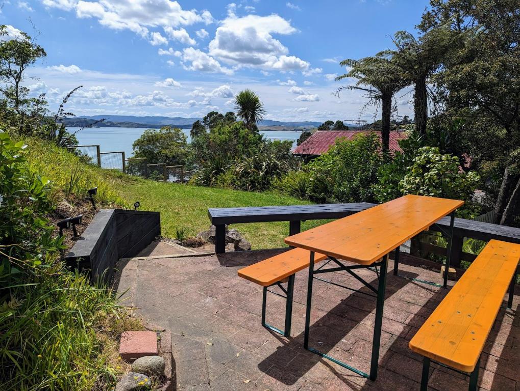 a wooden picnic table and two benches on a patio at Cox Bay Cottage in Raglan