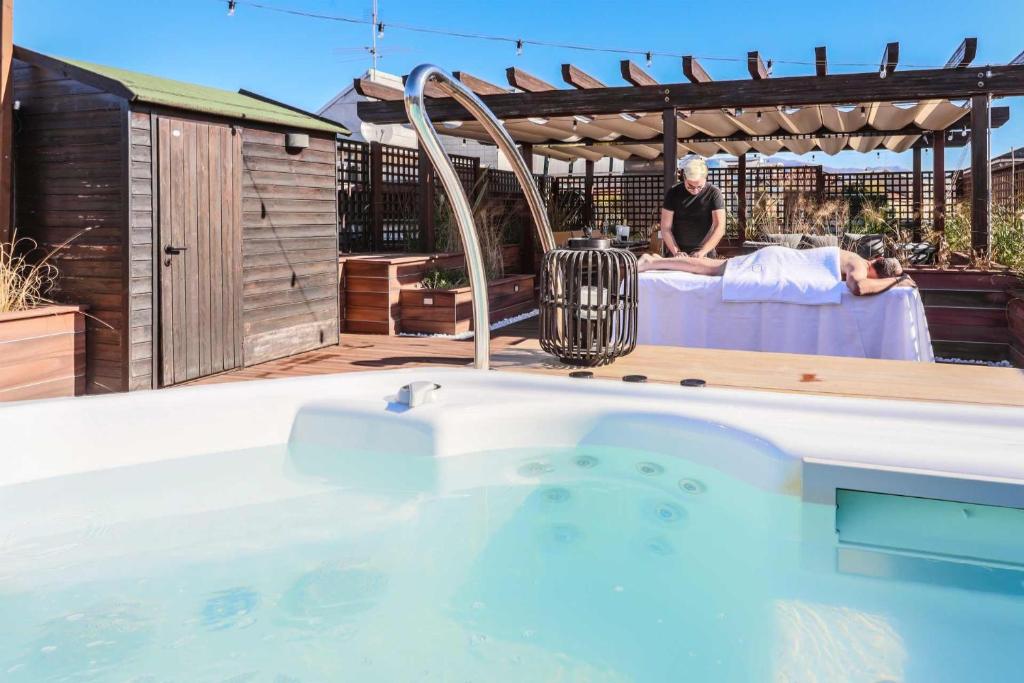 a man sitting on a table next to a swimming pool at AR Prestige Penthouse - Soho in Bergamo