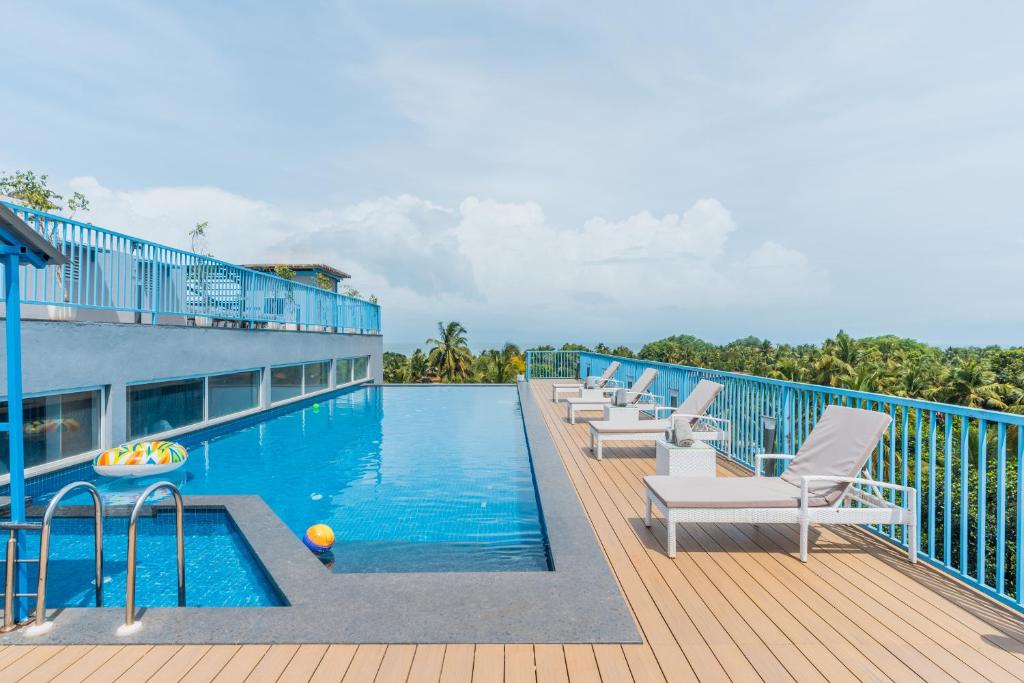 - une piscine avec des chaises longues sur une terrasse dans l'établissement De Mandarin Candolim Beach Goa, à Candolim