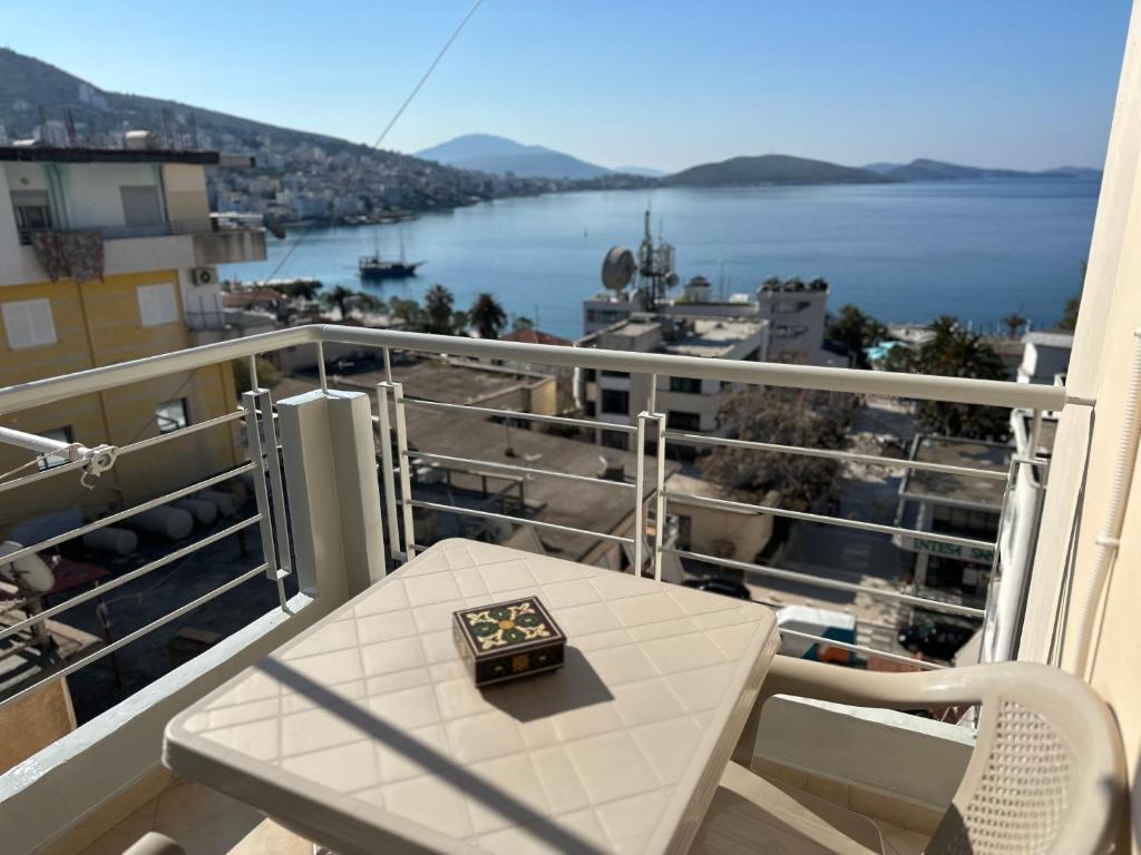 a table on a balcony with a view of the water at Comfort 1 Apartment in Sarandë