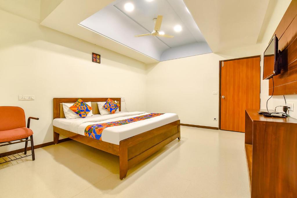 a bedroom with a bed and a tv and a chair at FabHotel Shivam, Karelibagh in Vadodara