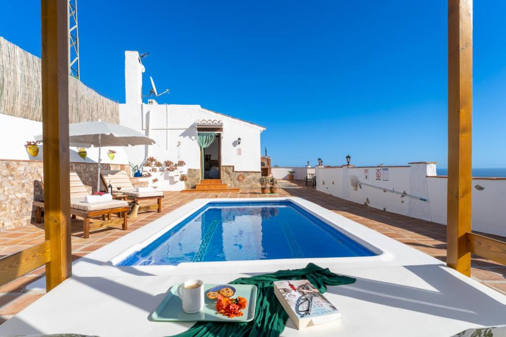 een villa met een zwembad en een tafel met een dienblad met eten bij Casa Herrero in Nerja