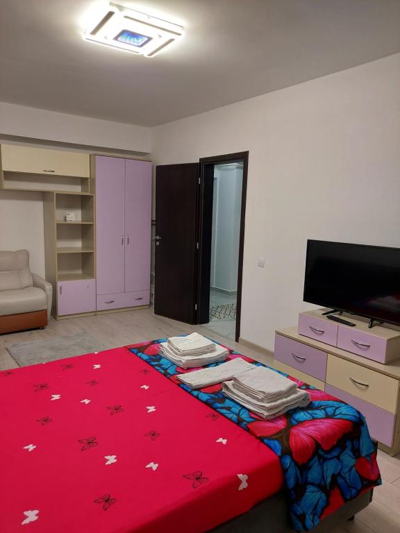 een slaapkamer met een grote rode deken en een tv bij Bya Brown Residence in Valea Lupului