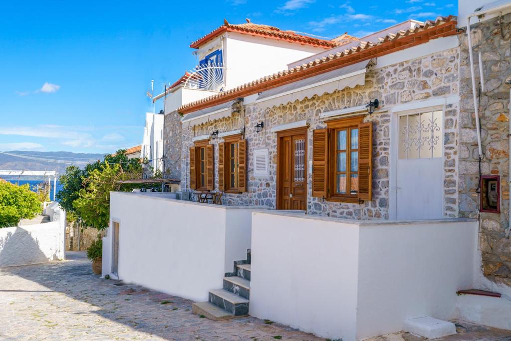 a white house with wooden windows on a street at Kamini - Hydra Dream Houses in Hydra