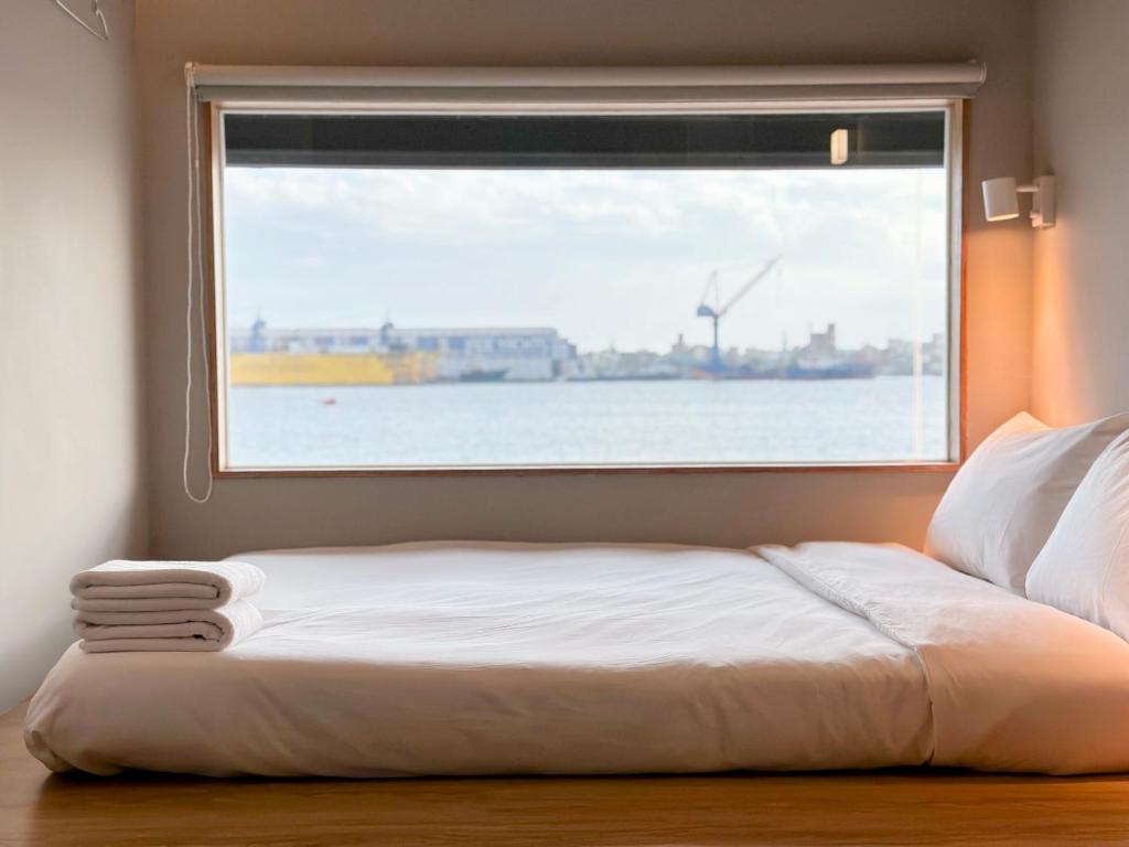 Bett in einem Zimmer mit einem großen Fenster in der Unterkunft KW2 Hostel in Kaohsiung