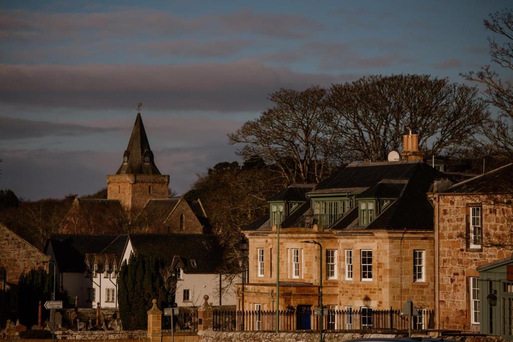 an old brick building with a tower and a church at Links House at Royal Dornoch in Dornoch
