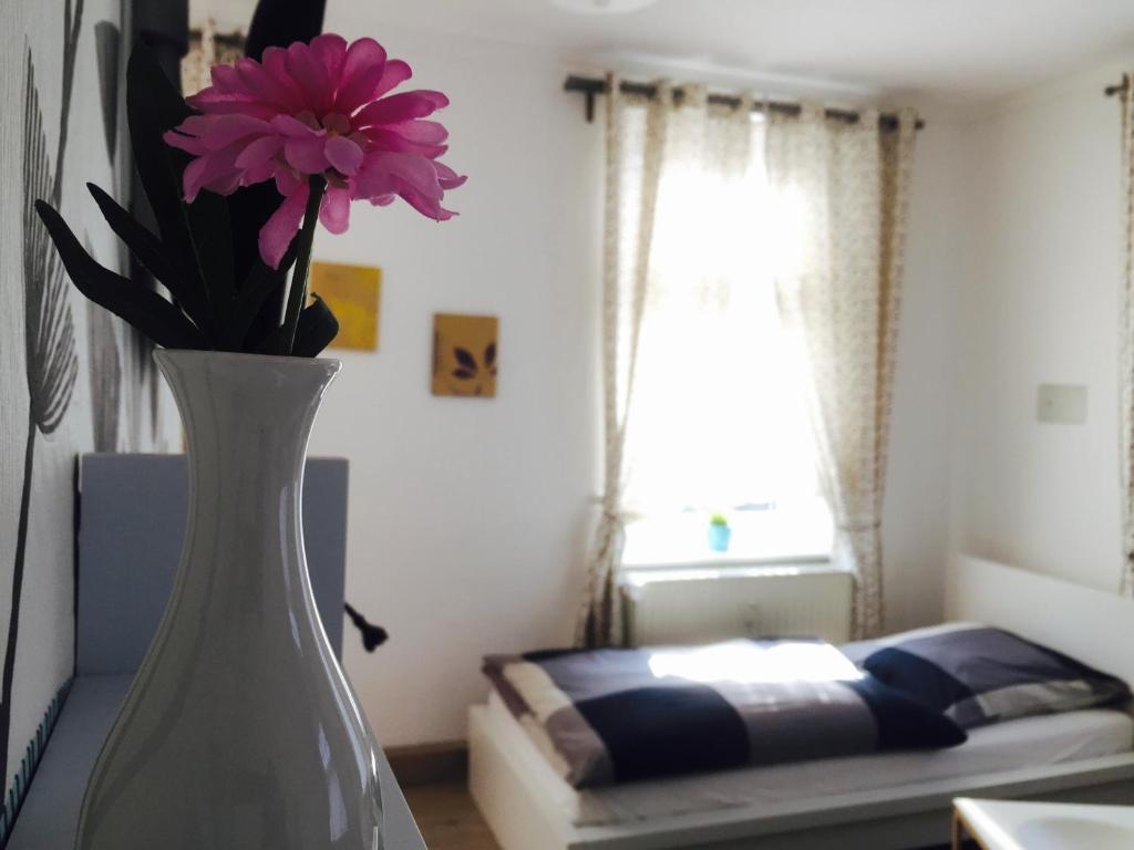 eine weiße Vase mit einer rosa Blume in einem Zimmer in der Unterkunft Rael-Boardinghouse in Bielefeld