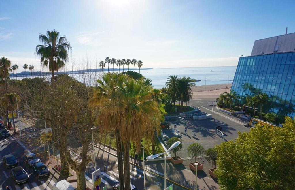 - une vue sur une plage bordée de palmiers et un bâtiment dans l'établissement LEM5D - Palmes d'Or Properties, à Cannes