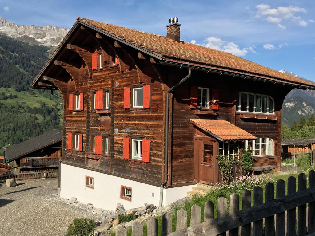 ein Holzhaus auf einem Hügel mit einem Zaun in der Unterkunft Charmantes Alpen-Appartement in Conters, Davos-Parsenn in Conters