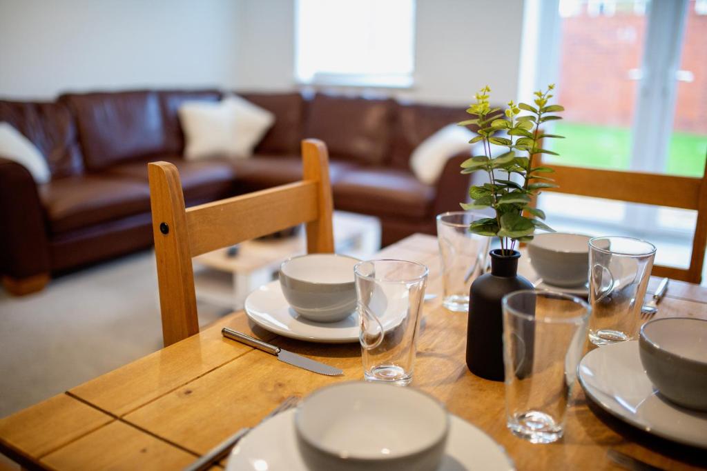 a wooden table with plates and glasses and a plant on it at Old Sarum House in Old Sarum