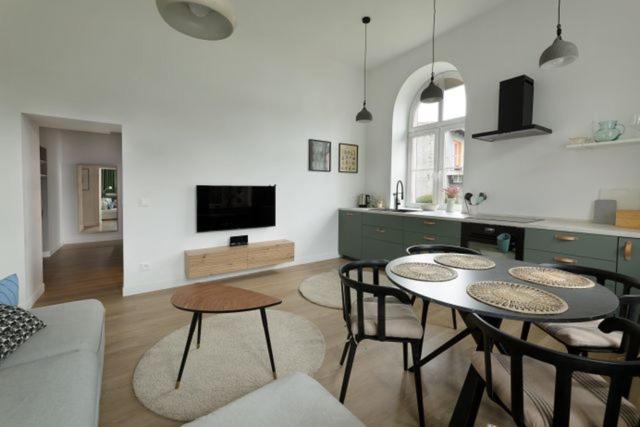 a living room with a table and chairs and a kitchen at Apartament Majowy w Centrum Kudowy in Kudowa-Zdrój