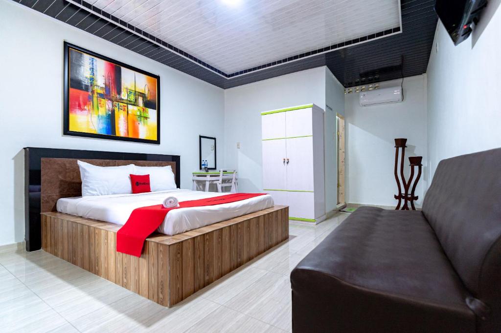 um quarto com uma cama e um sofá num quarto em RedDoorz near Universitas Simalungun Pematangsiantar em Pematangsiantar