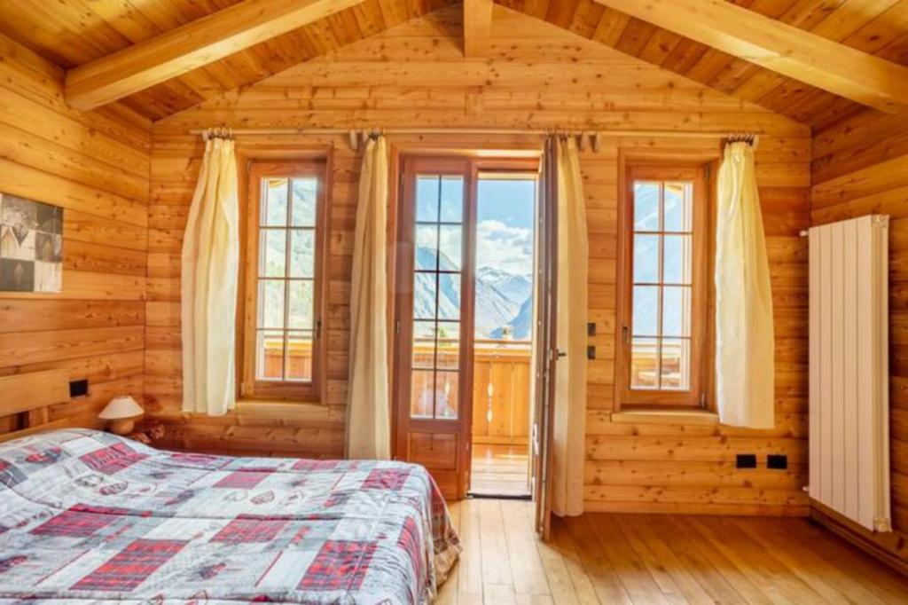 a bedroom with a bed in a room with windows at B&B Chalet Il Picchio in Varzo